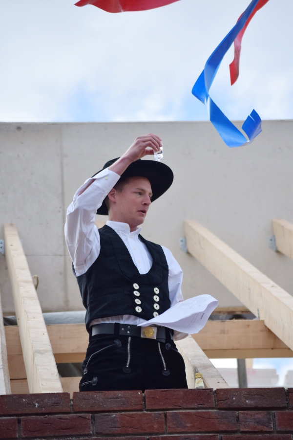 Der Zimmermann verliest den Richtspruch und erhebt das Glas auf den Bauherrn, die Baufirma und den Architekten.

